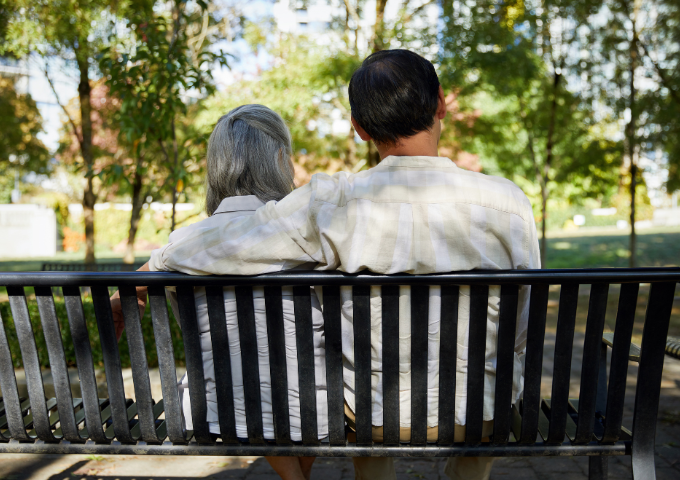 Two people on a bench, one with arm around the other