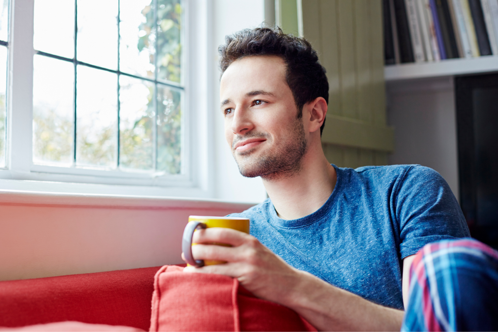 Man with mug looking out window
