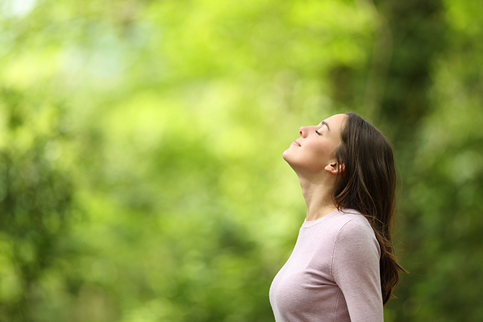 Woman deep breathing outside in nature