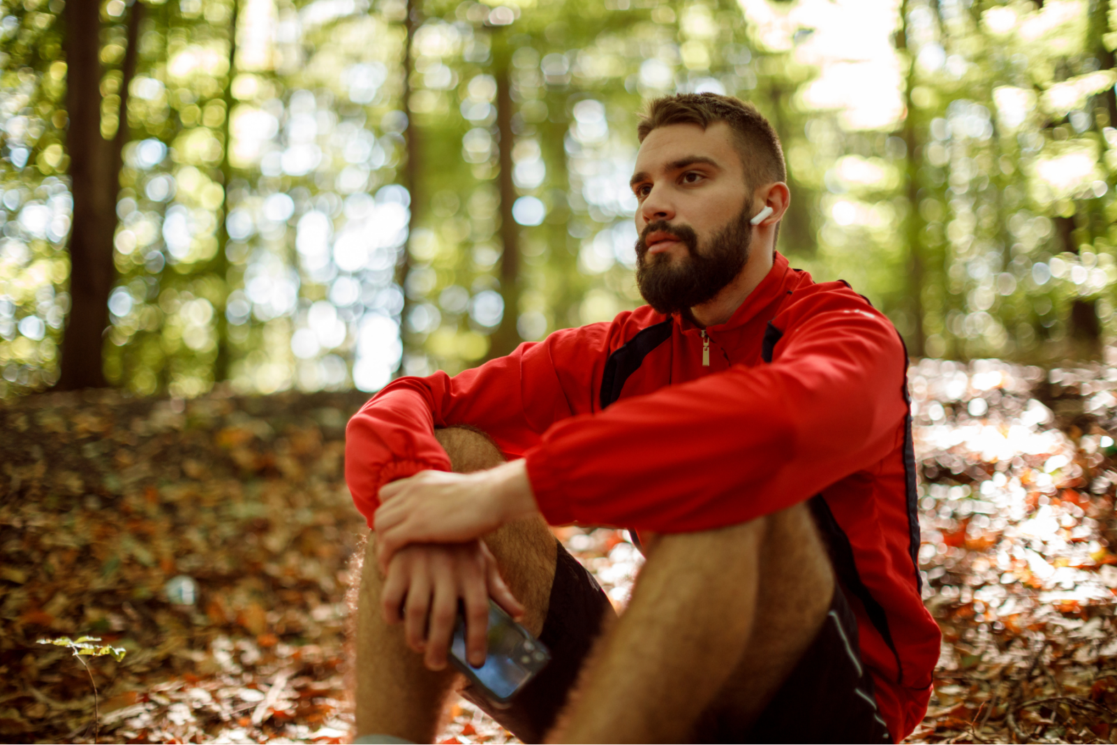Relaxed man with headphones on, sitting in a forest