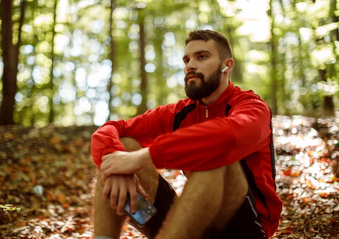 Relaxed man with headphones on, sitting in a forest